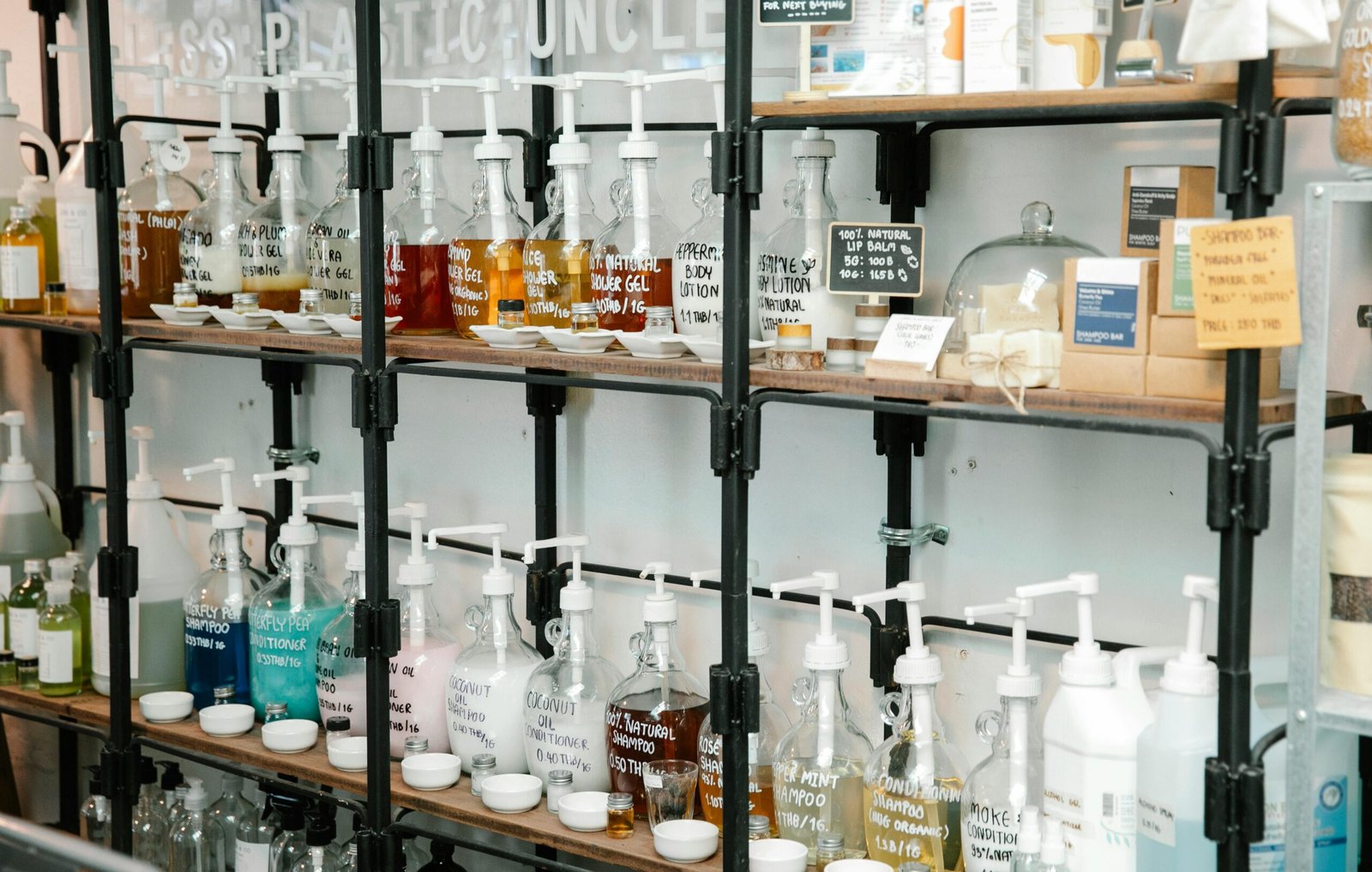 Collection of different plastic bottles with multicolored soap placed on shelves in zero waste shop